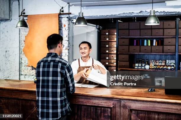 scatola di imballaggio del proprietario maschio mentre parla con il cliente - shopping male foto e immagini stock