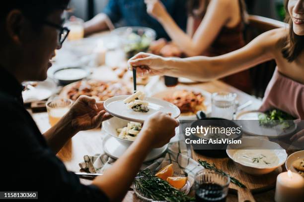 junge asiatische frau serviert pasta zu freunden während der party, sie haben spaß, plaudern und genießen essen und getränke - asiatische küche stock-fotos und bilder