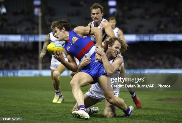 Josh Dunkley of the Bulldogs is tackled by David Mundy of the Dockers during the 2019 AFL round 19 match between the Western Bulldogs and the...
