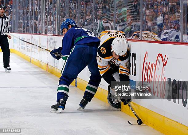 Kevin Bieksa of the Vancouver Canucks hip checks Milan Lucic of the Boston Bruins into the boards during Game Five of the 2011 NHL Stanley Cup Finals...