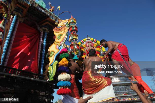 Tamil Hindu devotees place the idol of Lord Vinayagar into the large wooden chariot during the Vinayagar Ther Thiruvizha Festival at a Tamil Hindu...
