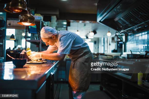 chef que sirve comida - cocina comercial fotografías e imágenes de stock