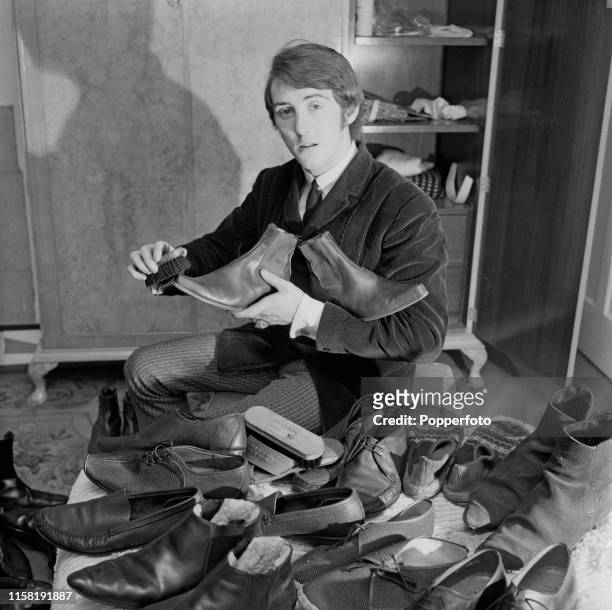English musician and singer Denny Laine, guitarist with The Moody Blues, pictured cleaning and polishing his collection of chelsea boots and shoes at...
