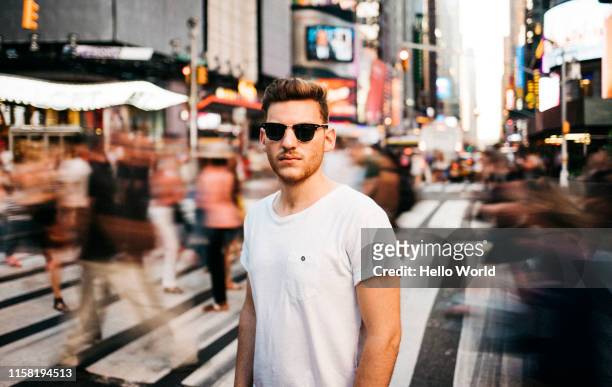 portrait of a tourist wearing sunglasses in a bustling city street in new york - beengt stock-fotos und bilder