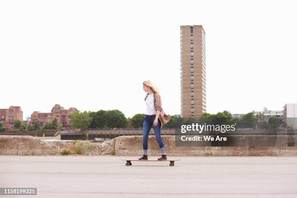 one young woman riding skateboard in city - longboard skating 個照片及圖片檔