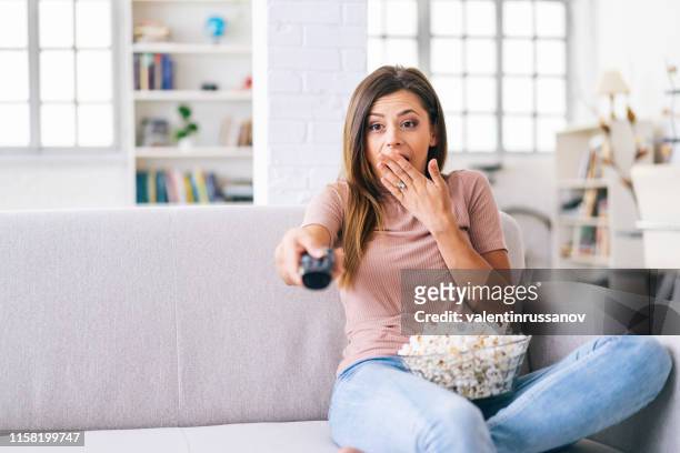 una donna spaventata che guarda la tv a casa - television show foto e immagini stock