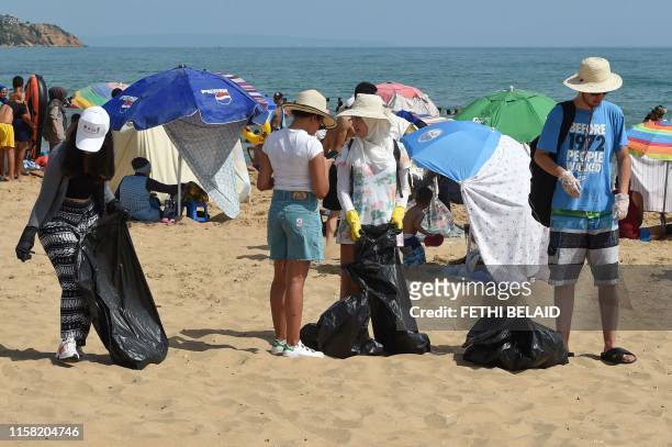 Volunteers of "CleanWalker" collect waste from a beach in the coastal town of Masra on July 14, 2019 near the capital Tunis. - Every sunday, dozens...