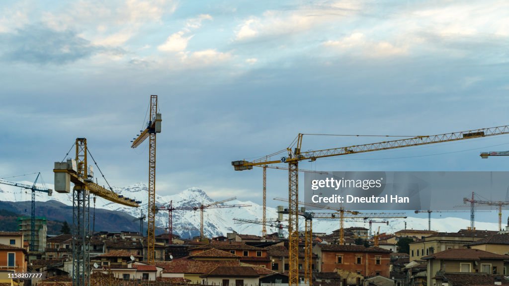 Damaged building and cranes in L'Aquila in the morning