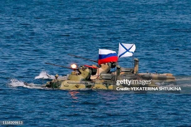 Russian armoured personnel carriers sail after submerging from an amphibious assault ship during a parade as part of the Navy Day celebration in...