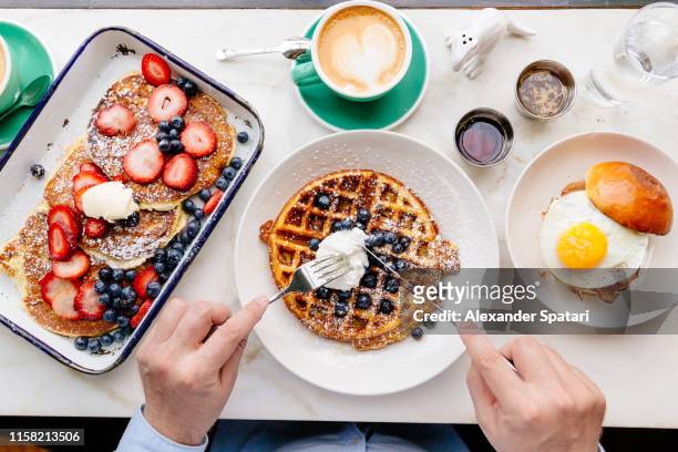 personal perspective directly above view of man eating breakfast at a cafe - blueberry pancakes stock-fotos und bilder