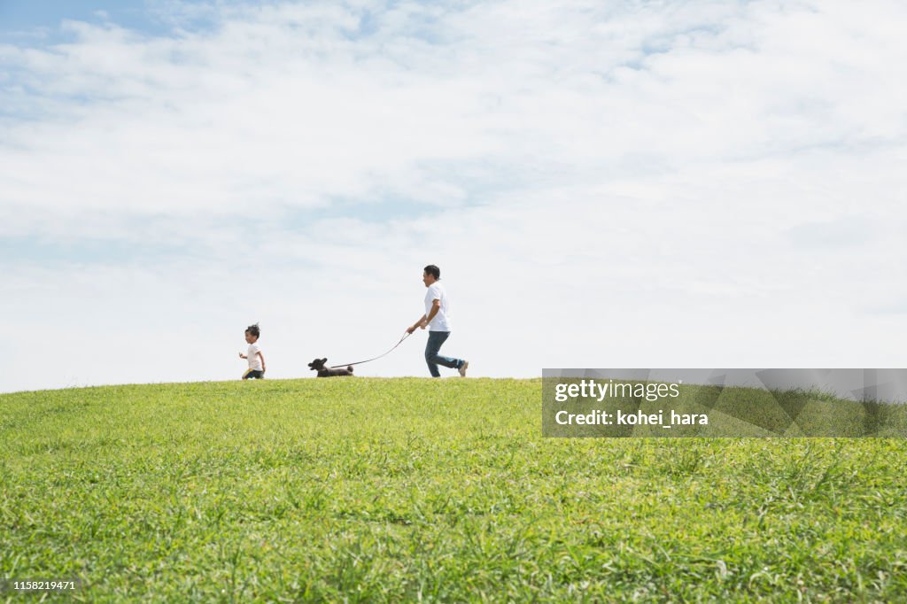 公園で一緒に犬を歩く父と息子