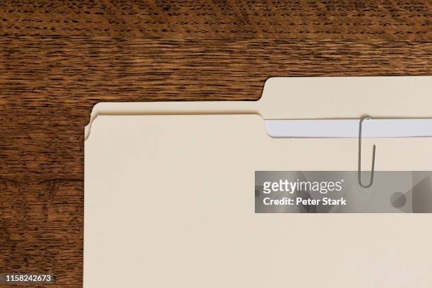 view from above manila folder and paperclip on wooden surface - pasta - fotografias e filmes do acervo