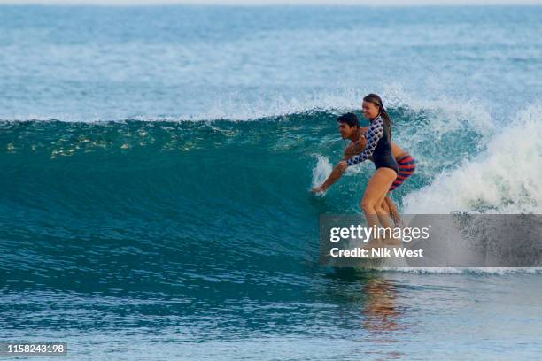 young couple sharing surfboard, surfing ocean wave - nayarit stock pictures, royalty-free photos & images