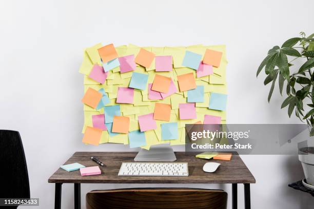 adhesive notes covering computer in office - information overload - fotografias e filmes do acervo