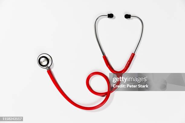 red stethoscope on white background - medical equipment stock pictures, royalty-free photos & images