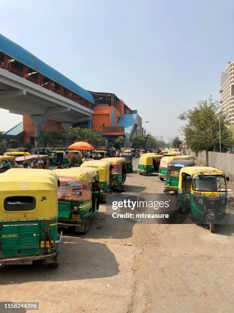 image of indian auto rickshaws taxi cab rank, yellow and green tuk tuks transport photo, parked in a row wave noida city centre, delhi metro, sector 32, noida, india - subway station stock pictures, royalty-free photos & images