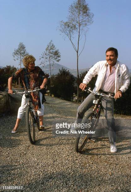 American Actor Stacy Keach rides his bike with his third wife 3 Jill Donahue along drive of their California home circa 1984;