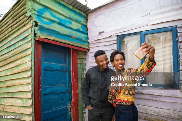 woman taking selfie with boyfriend in townships - south african culture stock pictures, royalty-free photos & images