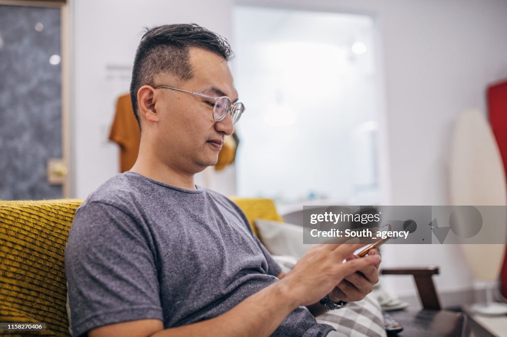 Man sitting in apartment and text messaging