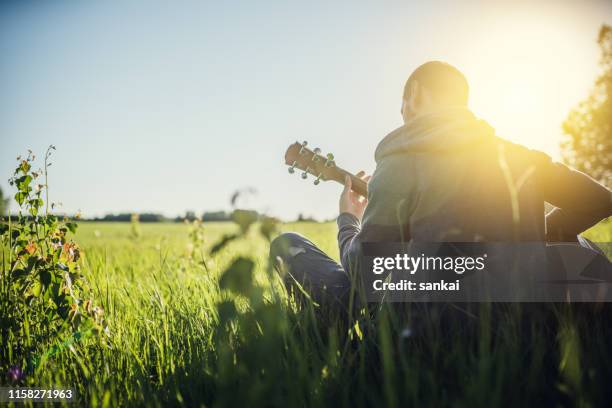 man playing acoustic guitar outdoors - musical instrument string stock pictures, royalty-free photos & images