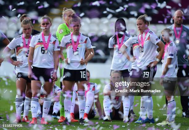 The Germany Women's U19 squad and coaches look on as the France Women's U19 team lift the European Championship trophy during the UEFA Women's...