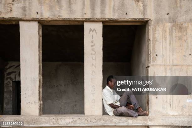 Man pages through his mobile phone while sitting at the Mohammed Goni Stadium internally displaced camp in Maiduguri, north-east Nigeria on July 26,...