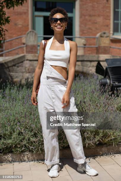 Guest is seen on the street attending 080 Barcelona Fashion week wearing white crop top, white overalls and white sneakers on June 25, 2019 in...