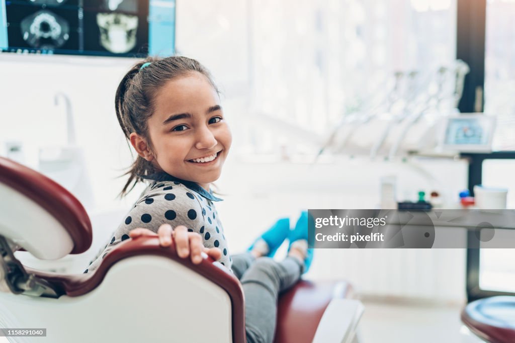 歯医者の椅子に座っている笑顔の少女の肖像画