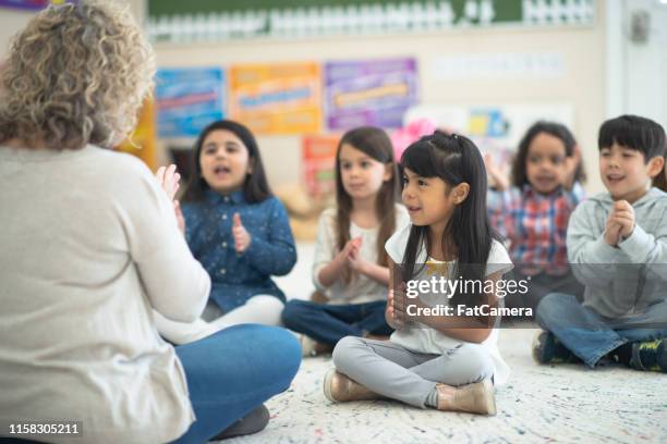 multiethnische gruppe von vorschulkindern tanzt zu musik mit ihrem kaukasischen lehrer - gesangslehrer stock-fotos und bilder