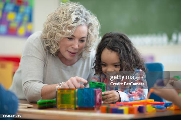 kaukasiska lärare spelar magnetiska block med sin etniska elev - preschool age bildbanksfoton och bilder