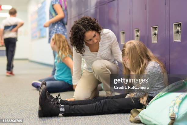 a teacher consoling a left-out student at an elementary school - showing compassion stock pictures, royalty-free photos & images