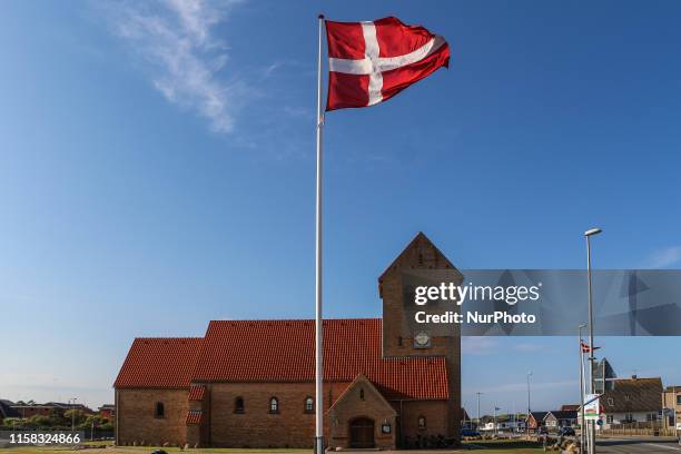 Big Denmark flag on the wind in front of church is seen in Hvide Sande, Denmark on 28 July 2019