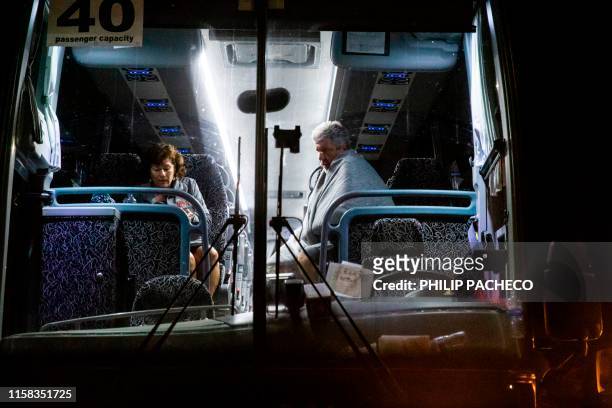 Evaucees Jane and Edward Jacobucci wait on a chartered bus after leaving the scene of the deadly Gilroy Garlic Festival shooting in Gilroy,...