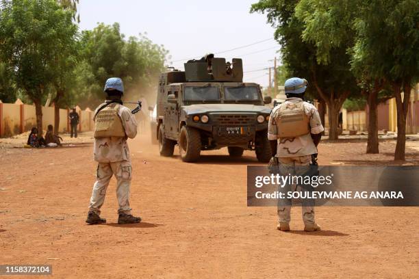 Senegalese soldiers of the UN peacekeeping mission in Mali MINUSMA patrol in the streets of Gao, on July 24 as an armoured vehicle of the FAMA drives...