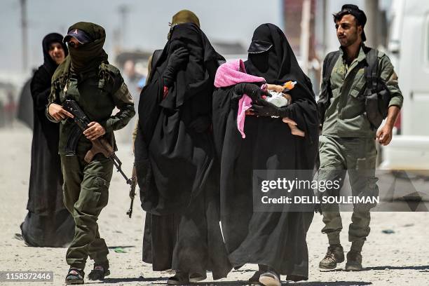 An internal security patrol escorts women, reportedly wives of Islamic State group fighters, in the al-Hol camp in al-Hasakeh governorate in...