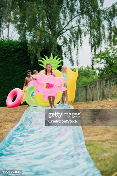 fun with inflatables on the slip 'n' slide - backyard water slide stock pictures, royalty-free photos & images