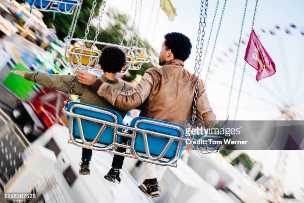 father and son riding swings at fun fair - festival day 11 fotografías e imágenes de stock