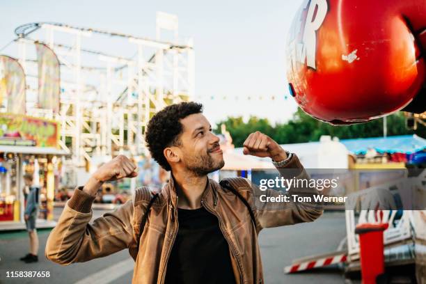 single dad flexing his arms at fun fair - carnival game stock-fotos und bilder