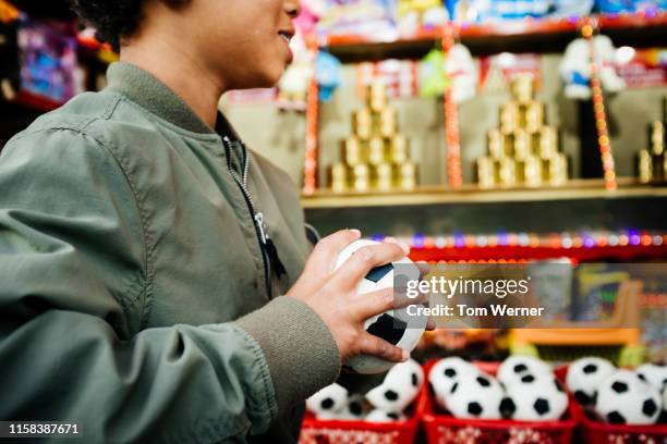 young boy holding soft ball at fun fair stall - fair game foto e immagini stock