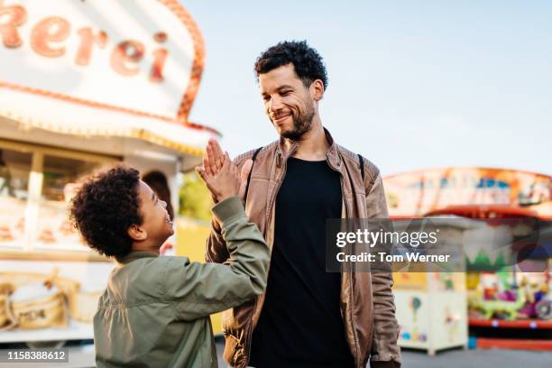 father and son high five at fun fair - carnival in germany foto e immagini stock