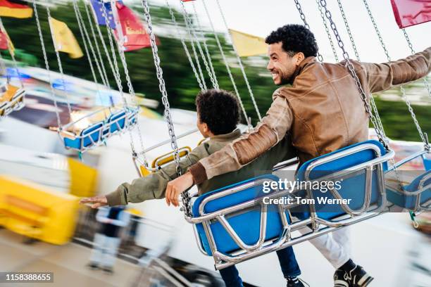 single dad sitting on swing ride with son - amusement park foto e immagini stock