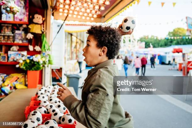 young boy throwing ball at fun fair game stall - festival day 11 fotografías e imágenes de stock