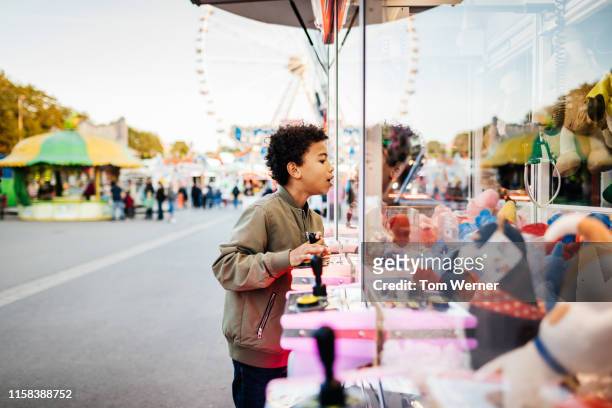 boy using claw machine at the fair - claw machine stock pictures, royalty-free photos & images