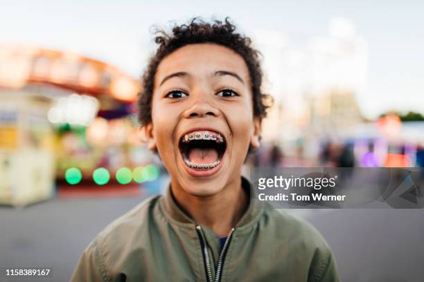 young boy with mouth wide open at fun fair - begeisterung stock-fotos und bilder