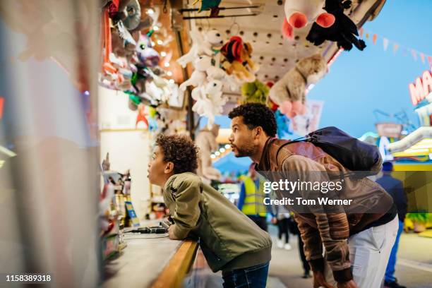 father and son choosing prize at fun fair game stall - games fair stock pictures, royalty-free photos & images