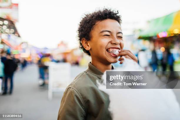 young boy with braces eating candy floss at fair - volksfest stock-fotos und bilder