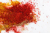 Variety of different ground spices in powder peppers paprika turmeric spilled in explosion effect on white marble stone background. Food ingredients aromatic flavorful condiments oriental cuisine