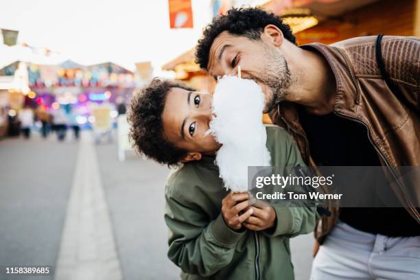 playful father and son sharing candy floss - happy family eating photos et images de collection