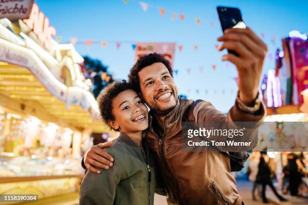single dad with son taking selfie at the fair - carnival celebration event stock pictures, royalty-free photos & images