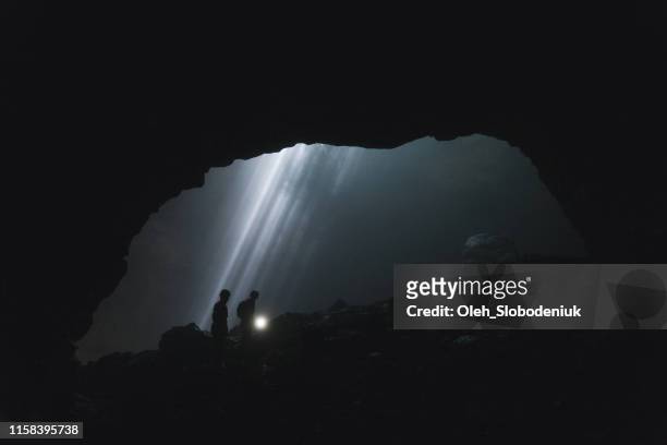 two people walking  in jomblan cave  on the background of sunbeams - cave stock pictures, royalty-free photos & images
